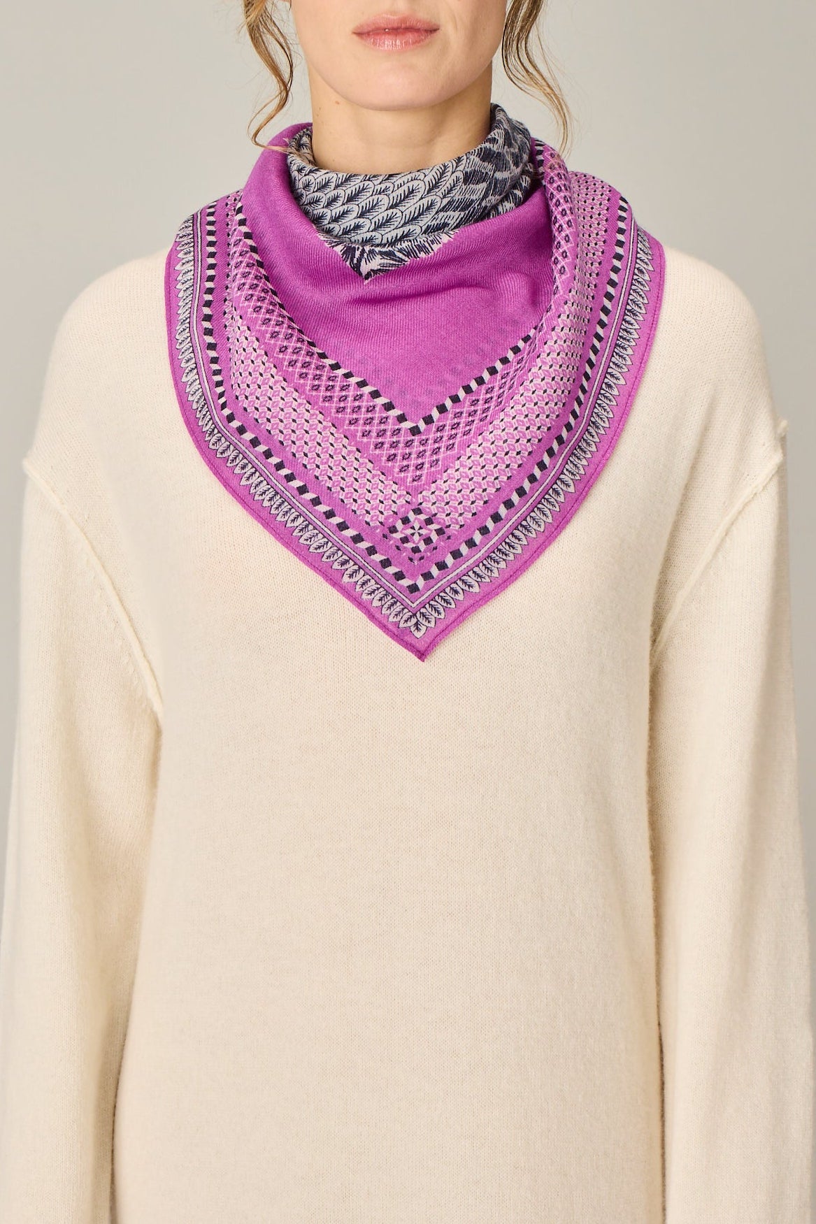 Woman wearing a purple scarf with a pattern on a plain background