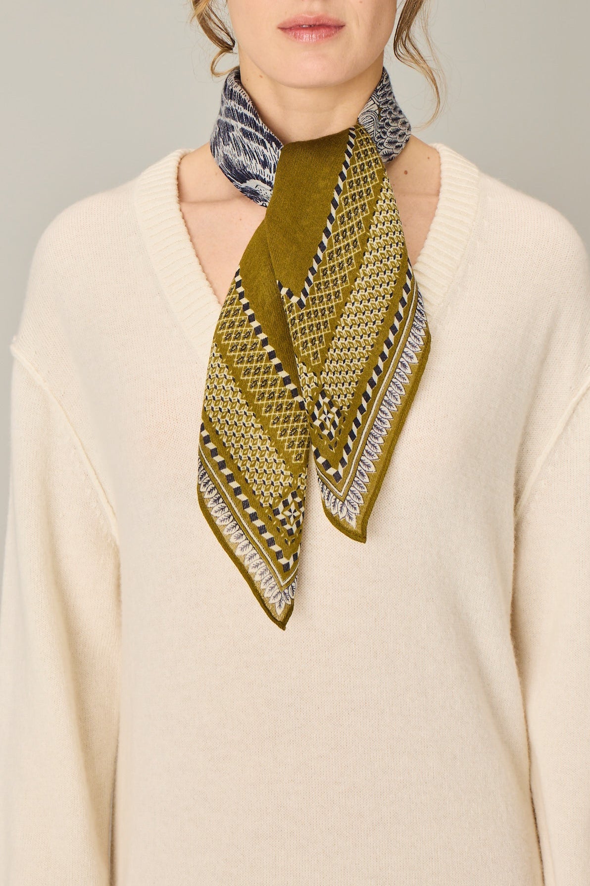 Woman wearing a green patterned scarf on a plain background