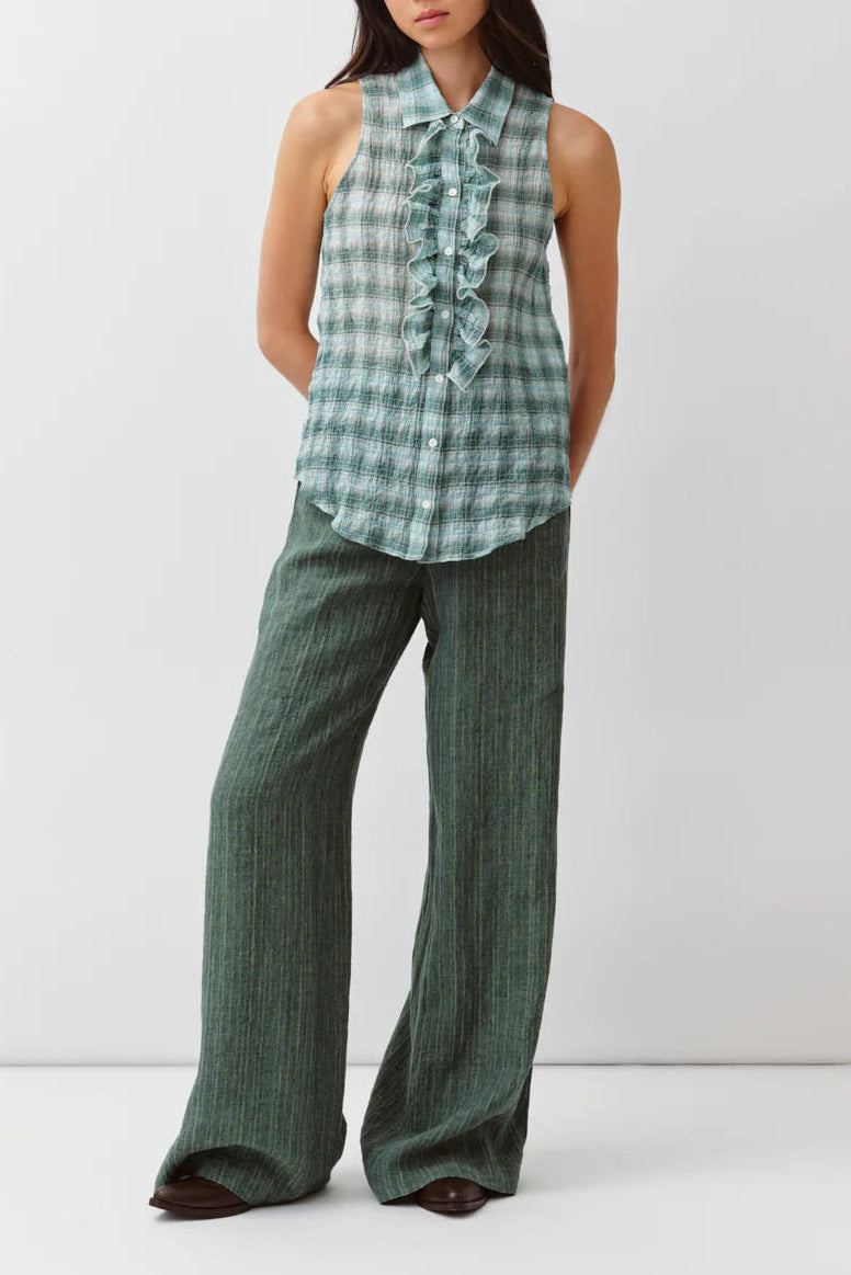 Woman wearing a green checkered top and wide-leg pants on a white background