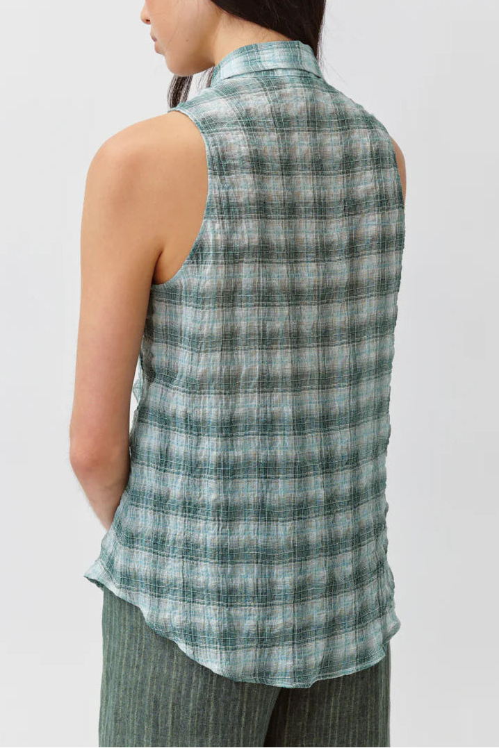 Woman wearing a sleeveless plaid shirt against a white background