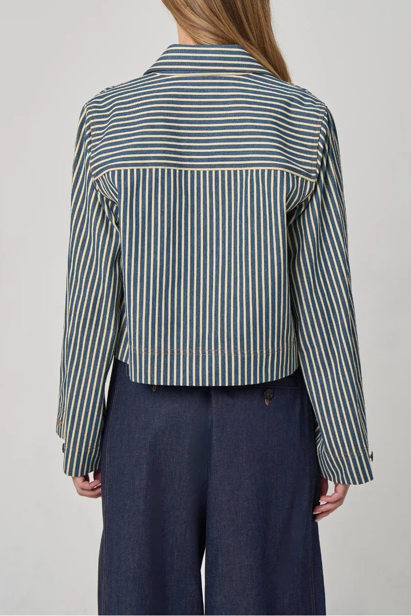 Person wearing a striped shirt and dark pants on a plain background
