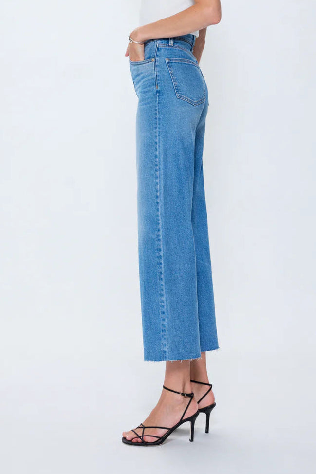 Woman wearing a white top and blue jeans on a white background