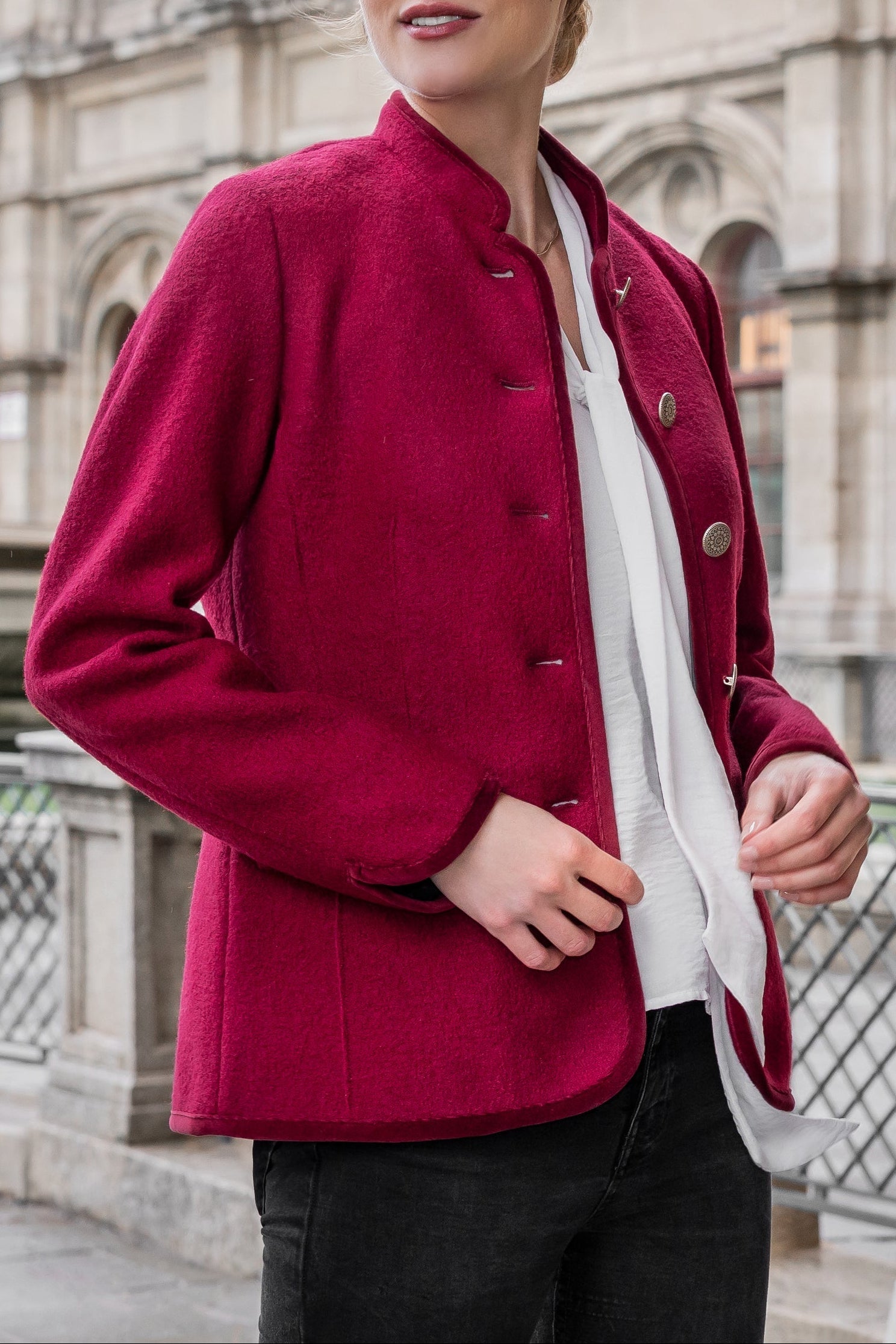 Woman wearing a red jacket in front of an architectural building