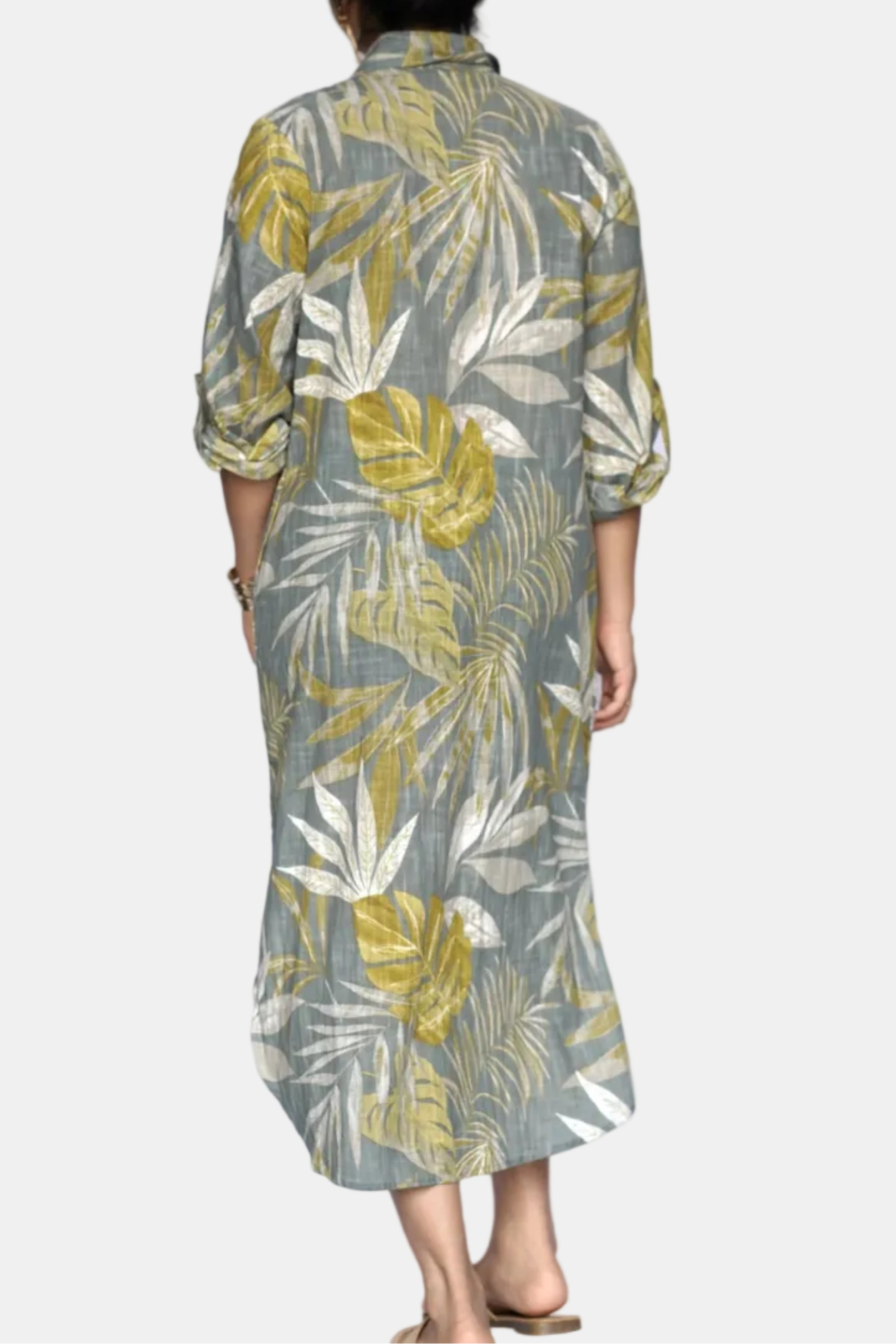 Person wearing a green and yellow leaf-patterned dress on a white background