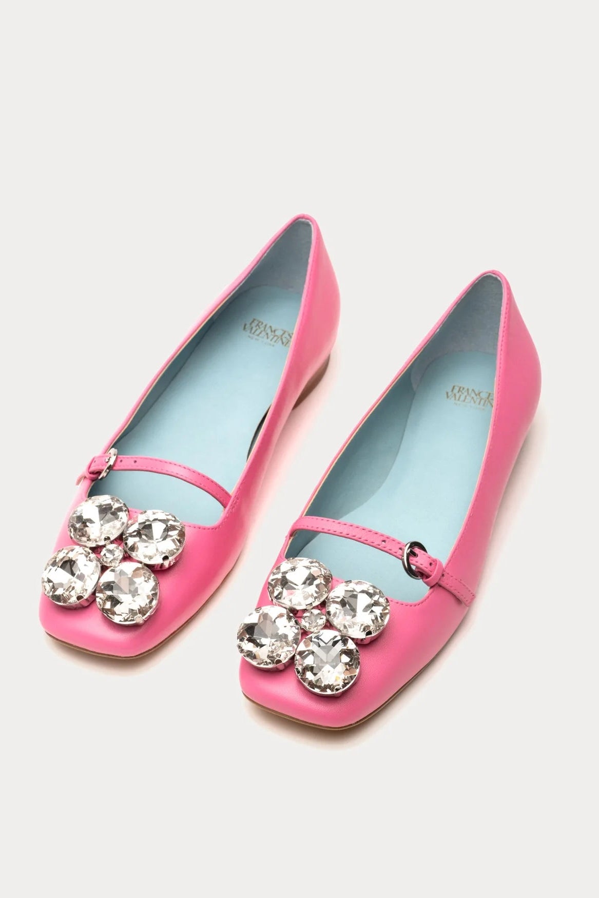 Pink shoes with crystal embellishments on a light gray background