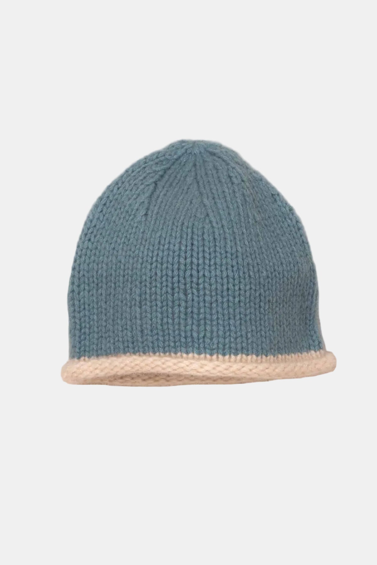A blue and beige knit beanie hat with a solid blue upper section and a contrasting beige ribbed brim, displayed on a textured beige fabric background.