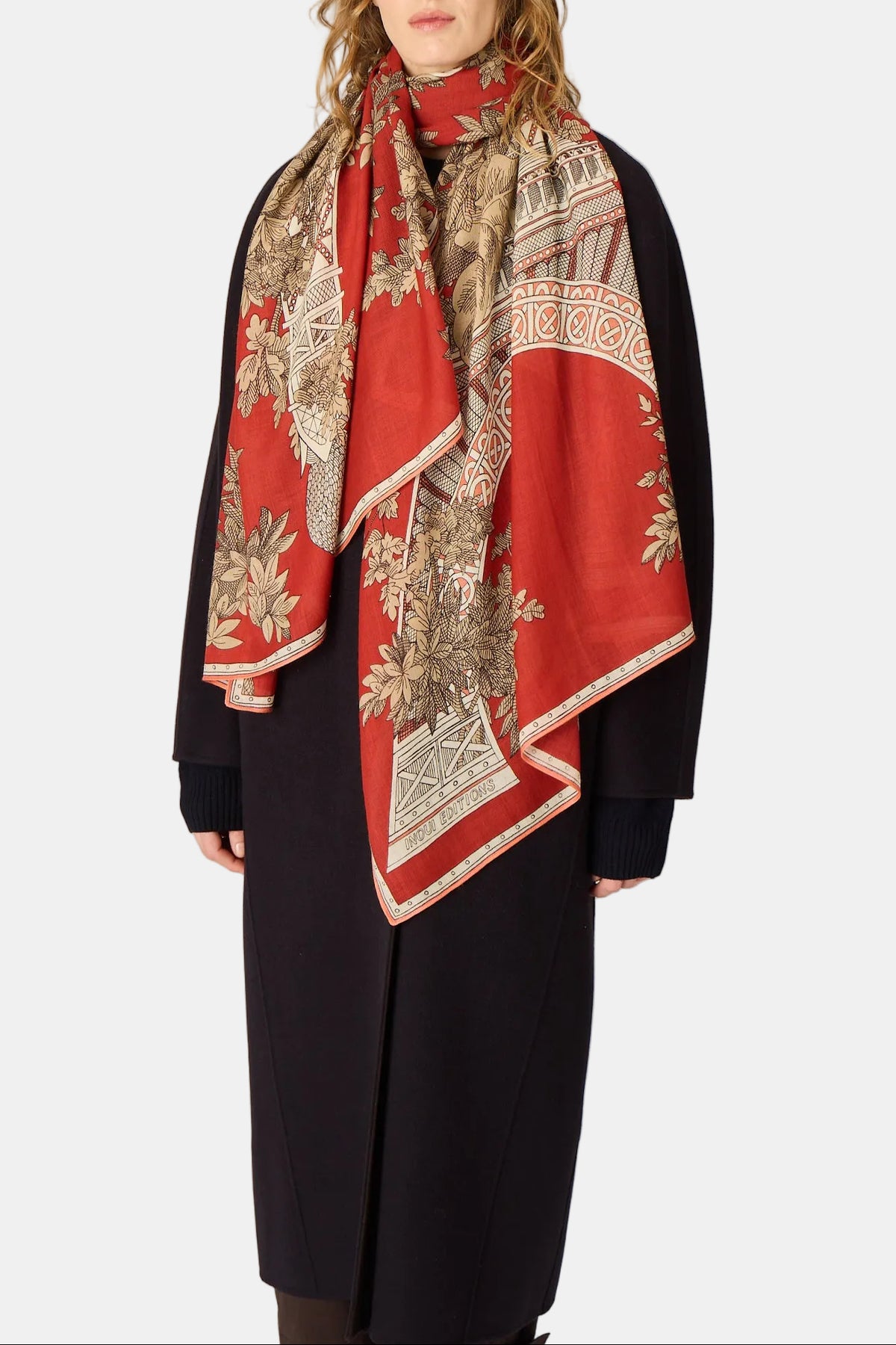 Woman wearing a red and patterned scarf with a plain background