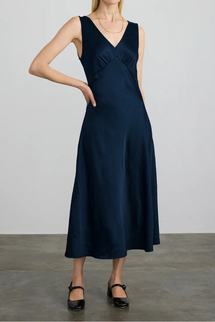Woman wearing a navy blue dress against a plain background
