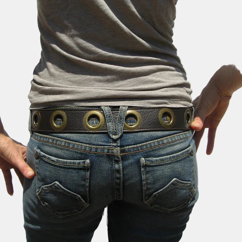 Person wearing blue jeans with a decorative belt on a white background
