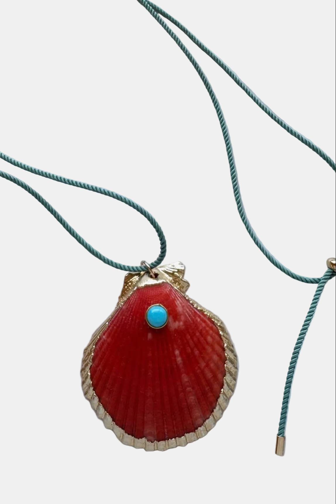 Necklace with a red shell pendant and turquoise stone on a marble surface