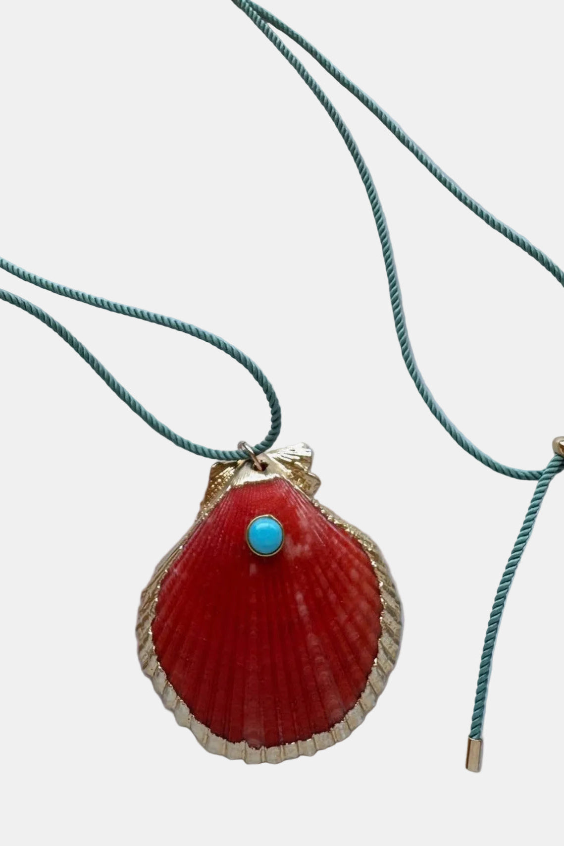 Necklace with a red shell pendant and turquoise stone on a marble surface