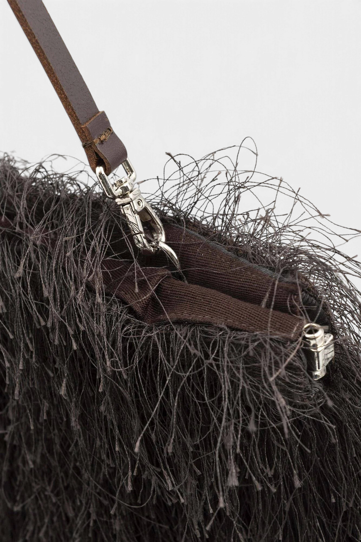 Close-up of a brown leather strap with metal hardware on a textured surface.