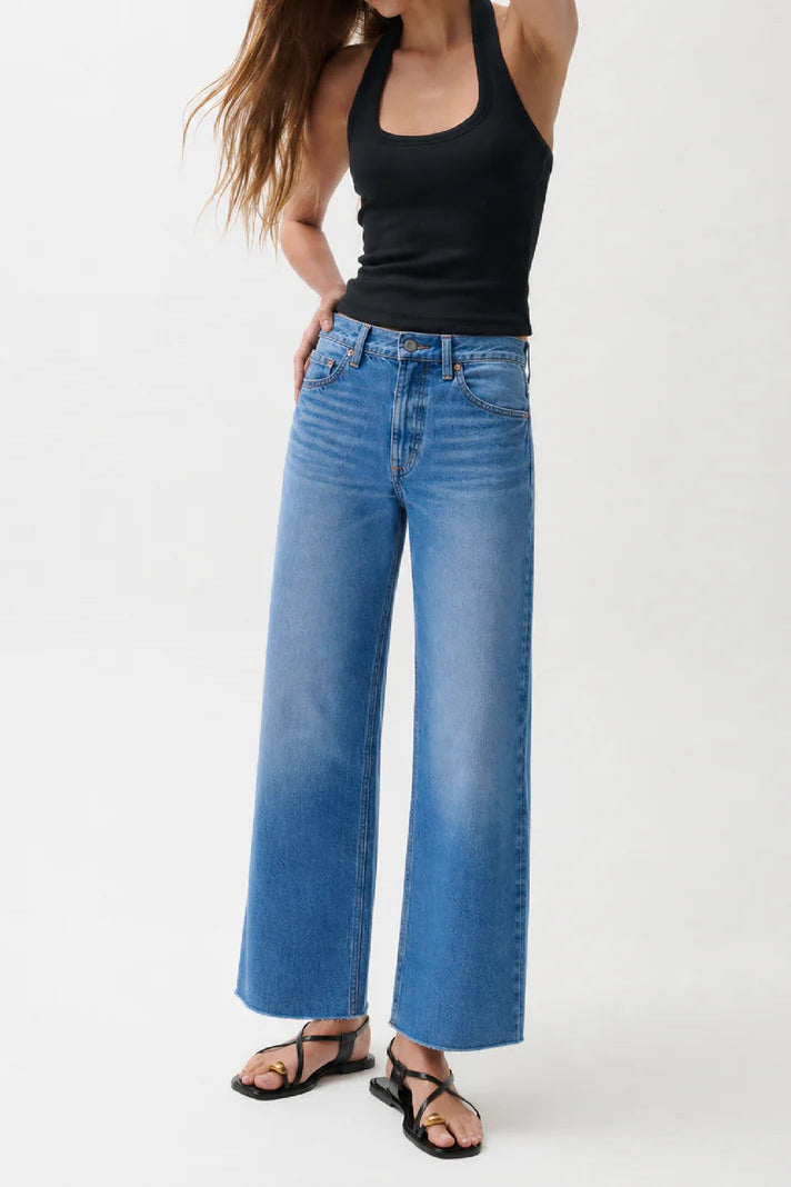 Woman wearing a black tank top and blue jeans on a white background