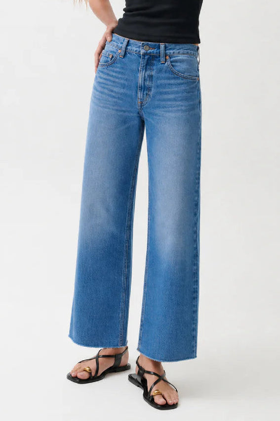 Woman wearing a black tank top and blue jeans on a white background