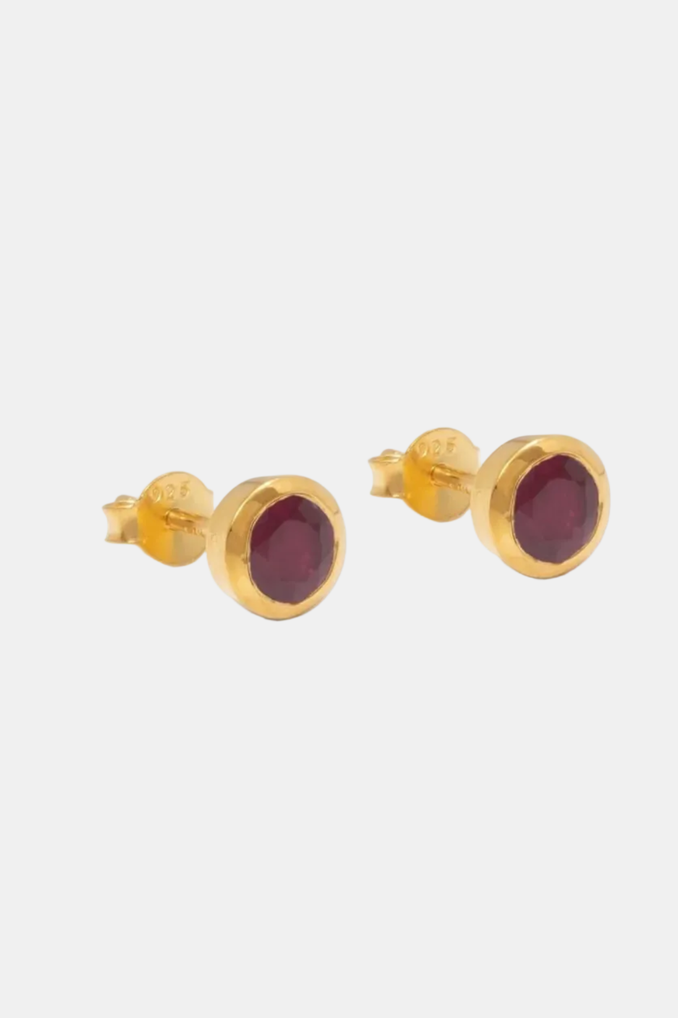 Gold stud earrings with red gemstones on a white background