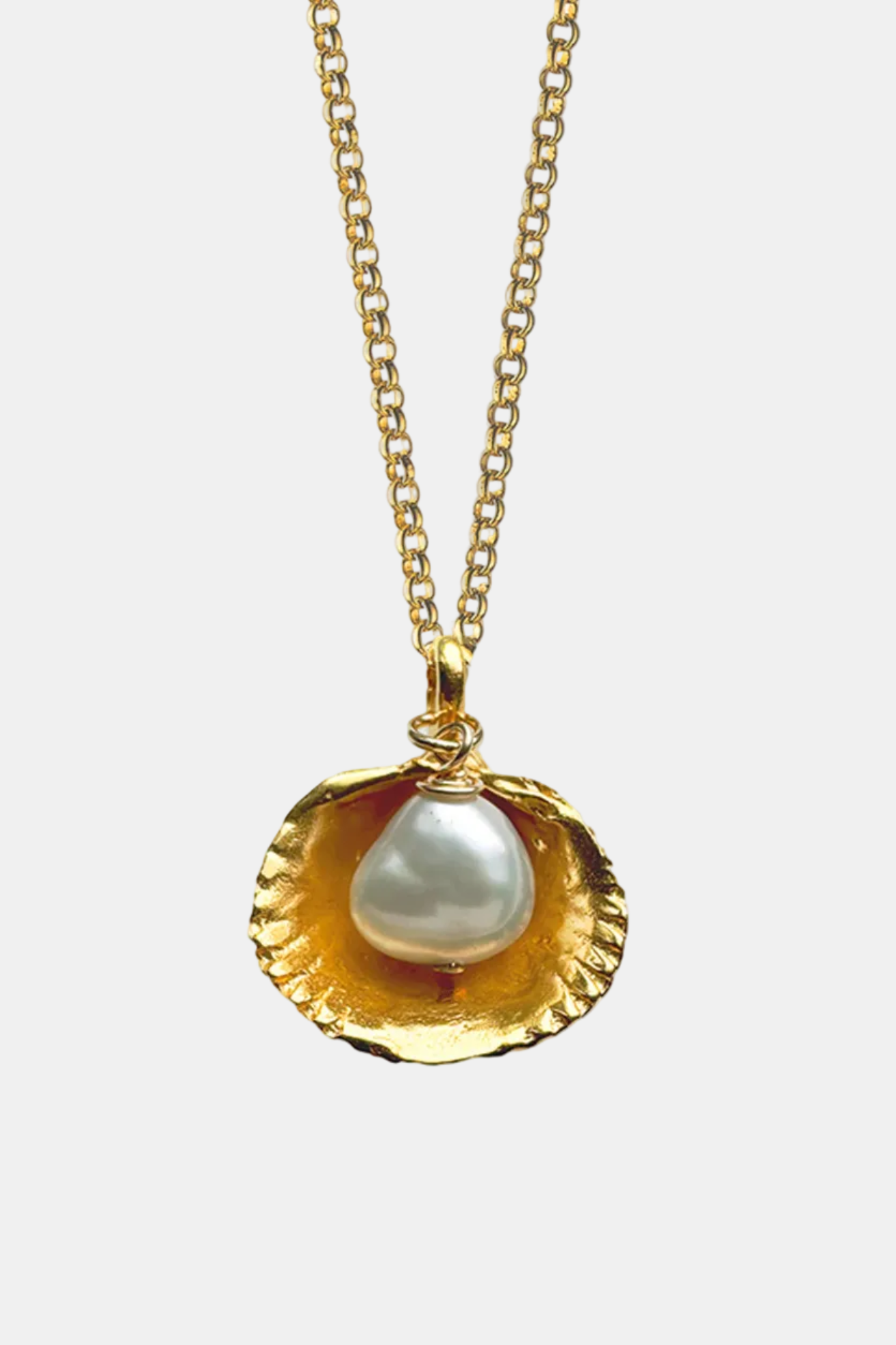 Gold necklace with a shell pendant featuring a pearl on a white background