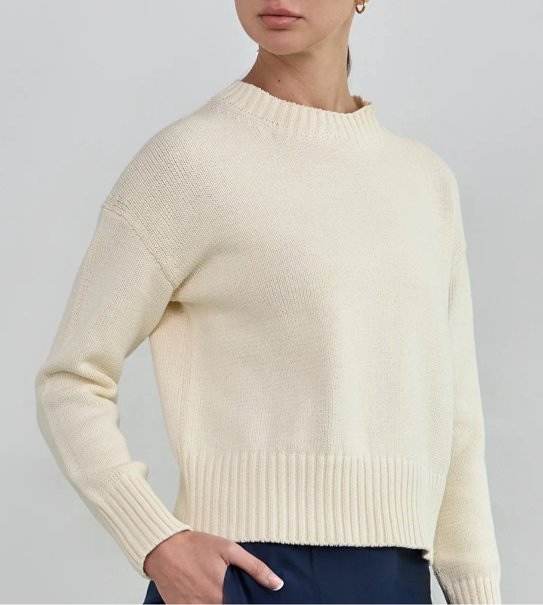 Woman wearing a cream sweater against a plain background