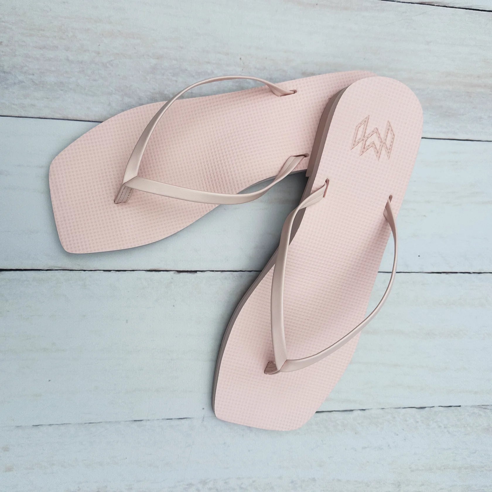 Pair of pink flip-flops on a light blue wooden surface
