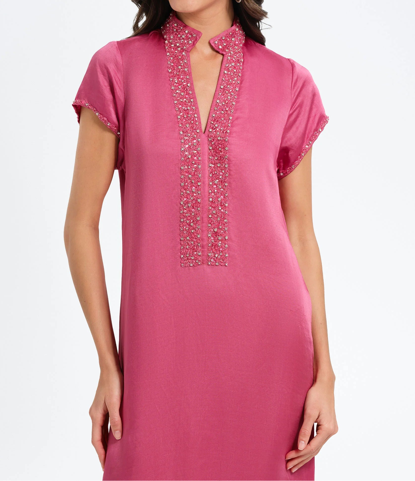 Woman wearing a pink dress with beaded neckline on a white background