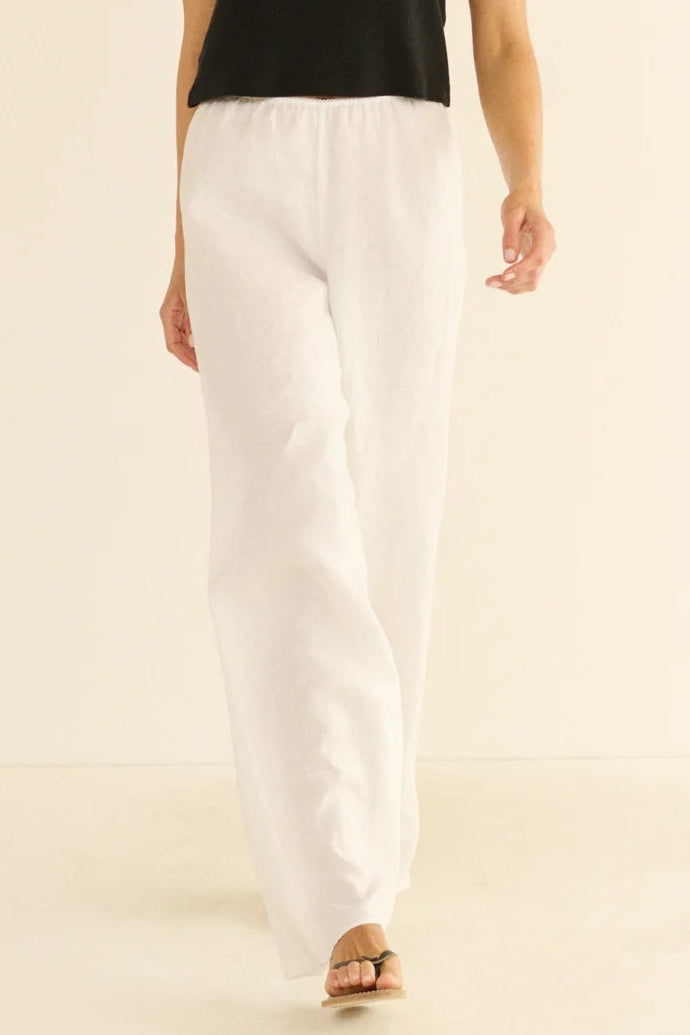 Woman wearing a black t-shirt and white pants on a beige background