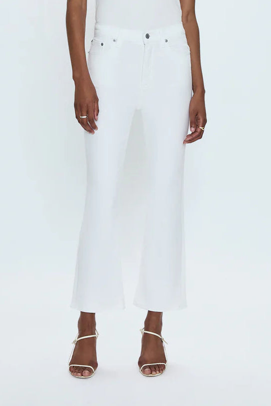 Woman wearing a white sleeveless top and white pants on a light gray background
