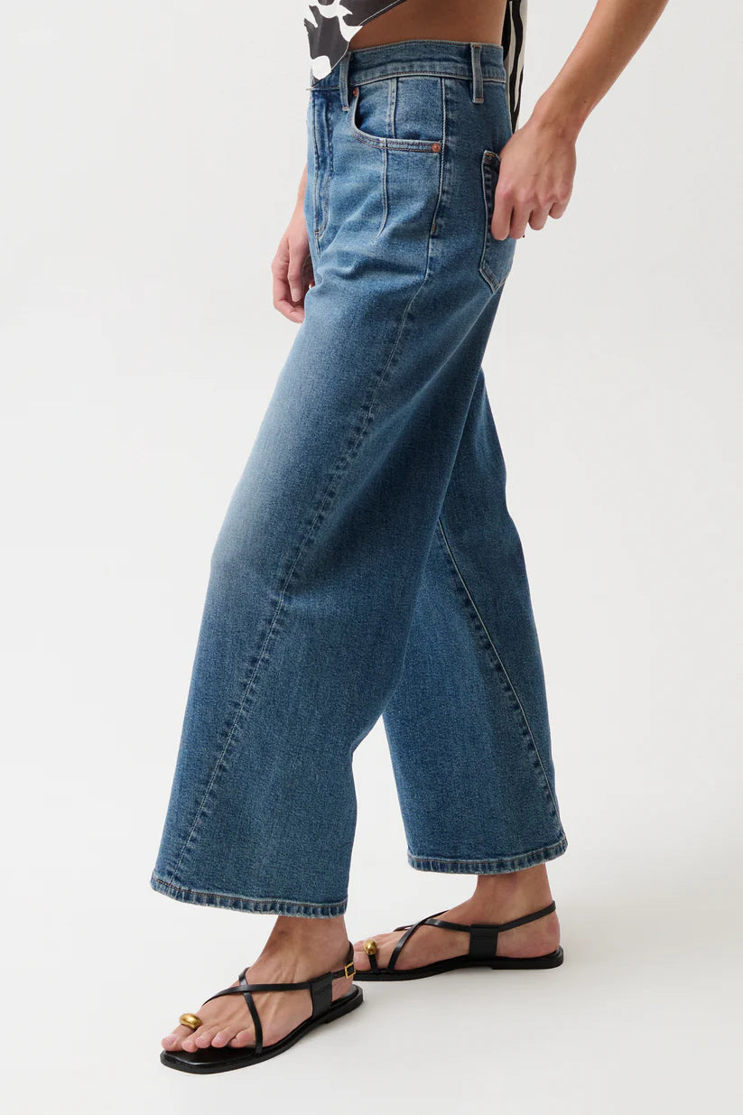 Person wearing blue wide-leg jeans on a white background