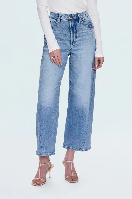 Person wearing a white long-sleeve top and light blue jeans on a white background