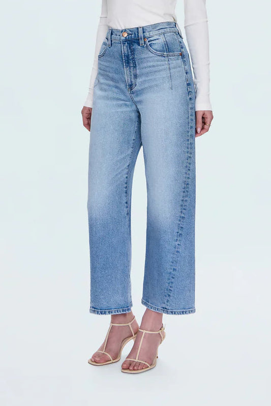 Woman wearing light blue jeans and a white top on a white background