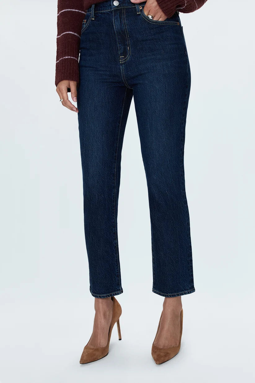 Person wearing dark blue jeans and brown high-heeled shoes on a white background