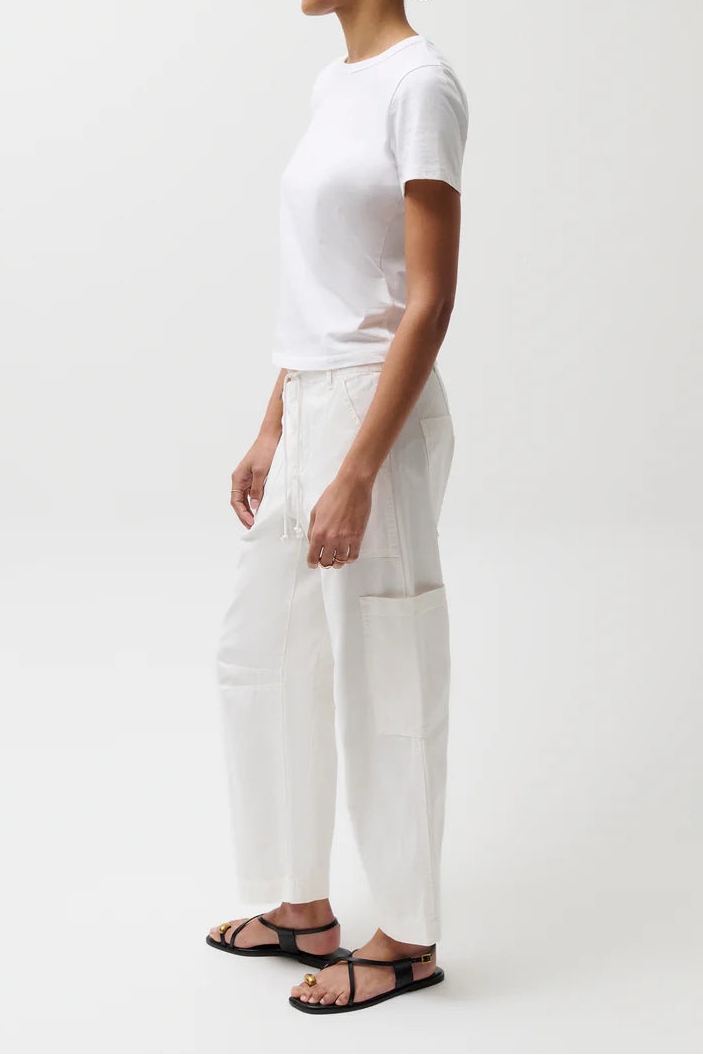 Person wearing a white t-shirt and pants with a green cap on a white background