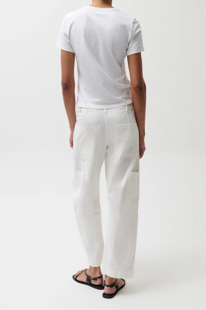 Person wearing a white t-shirt and white pants with a green cap on a white background