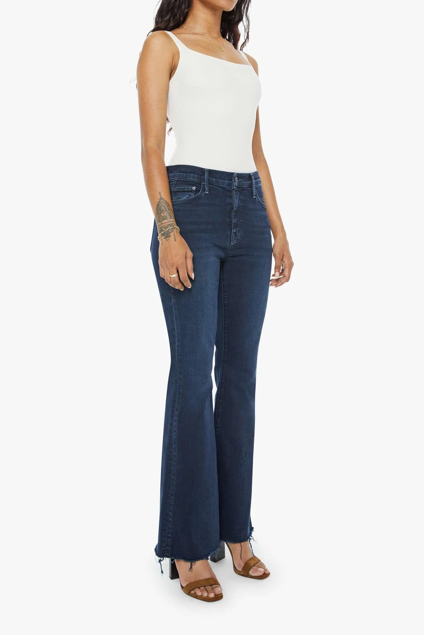 Woman wearing a white tank top and dark blue jeans on a white background
