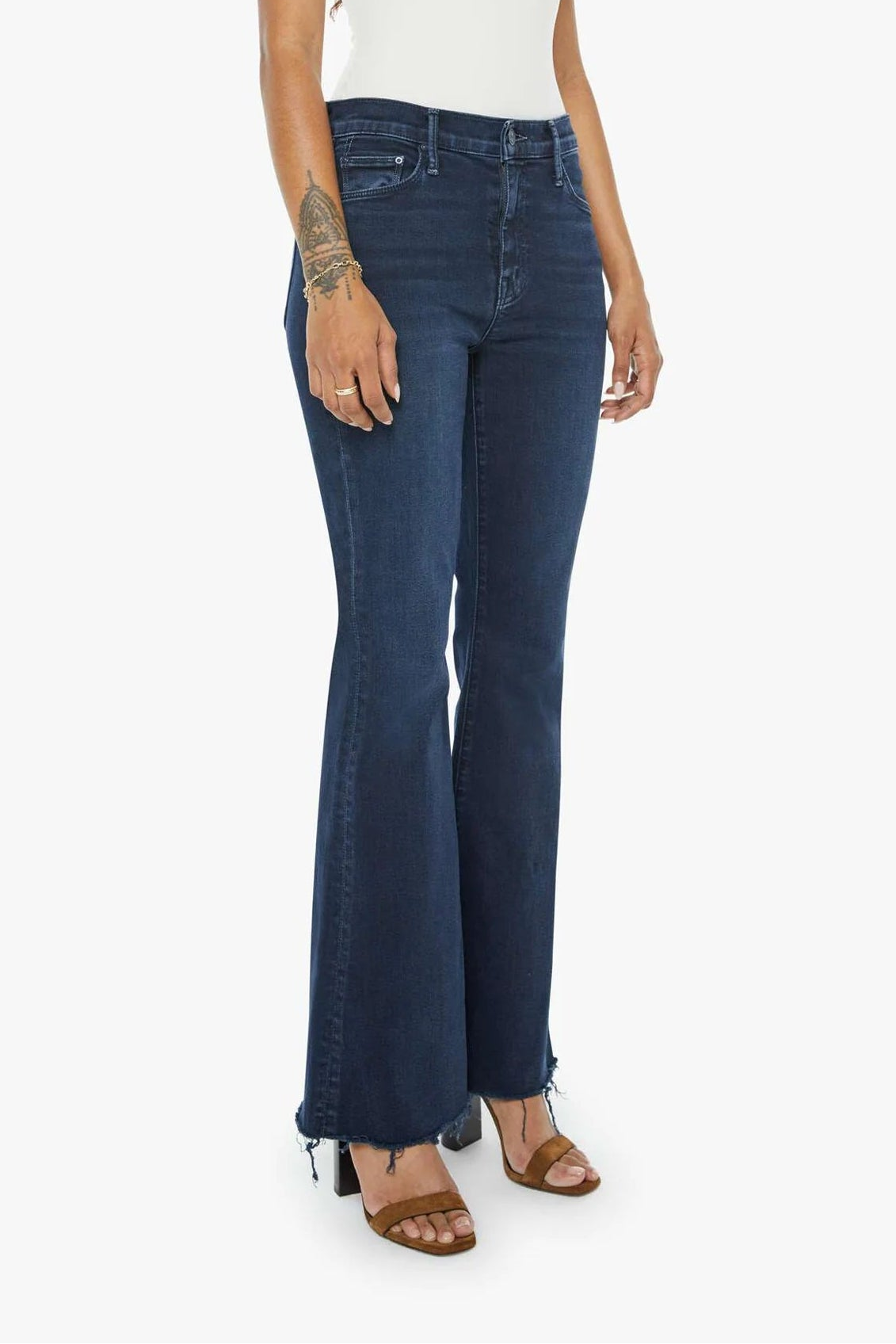 Woman wearing a white tank top and dark blue jeans on a white background