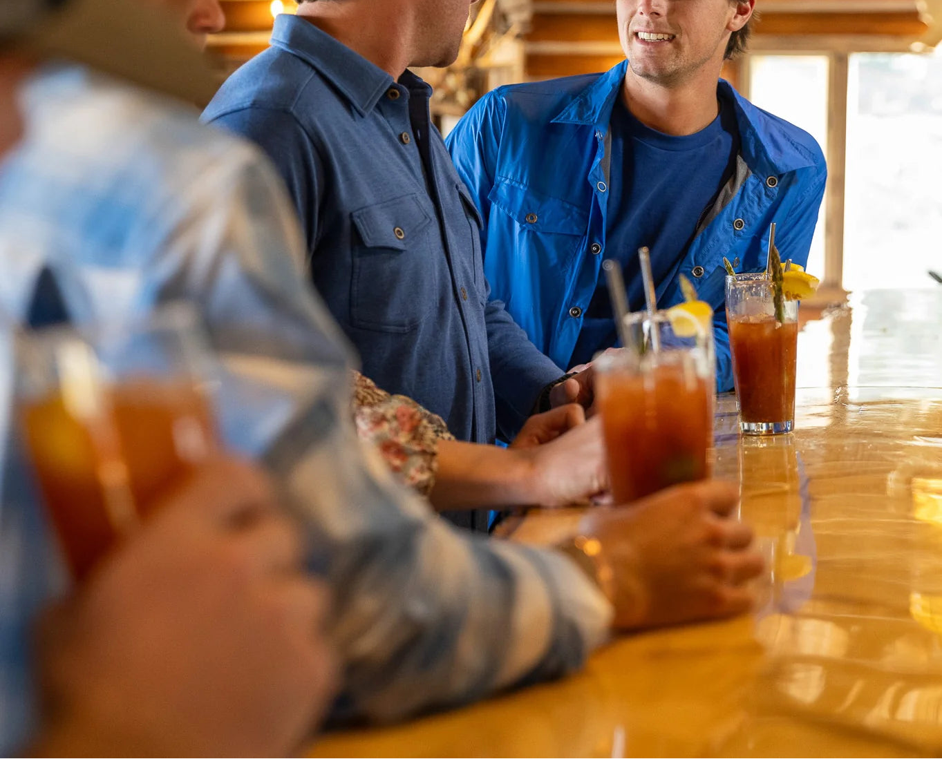 Three men sitting at a table with drinks, engaged in conversation.