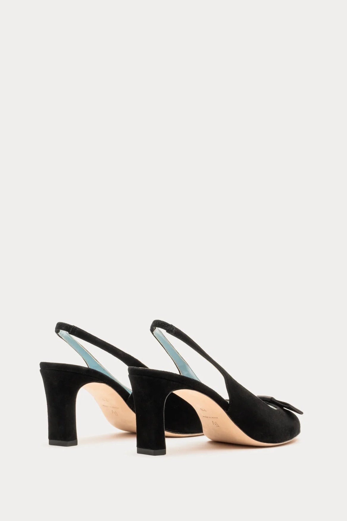 Black high-heeled slingback shoes on a light gray background