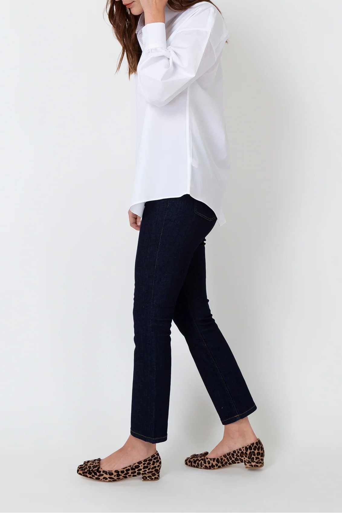 Woman wearing a white blouse and dark pants with leopard print shoes on a white background