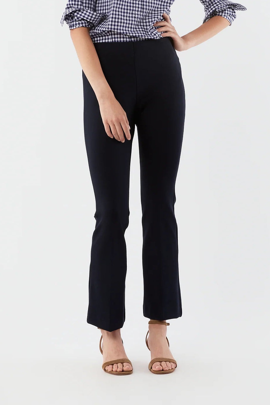 Woman wearing a checkered shirt and black pants on a white background
