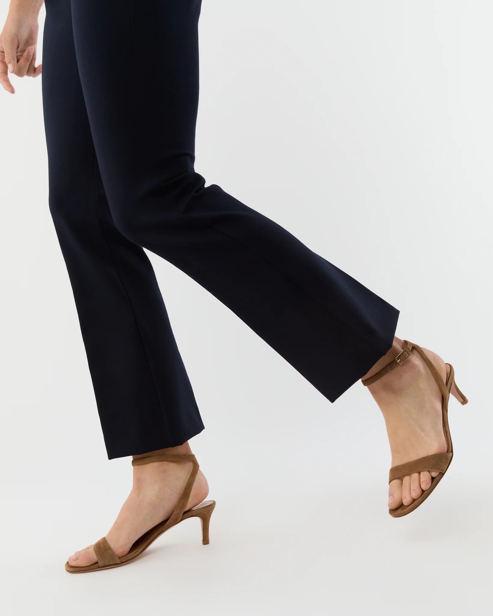 Navy pants worn with brown open-toe shoes on a white background