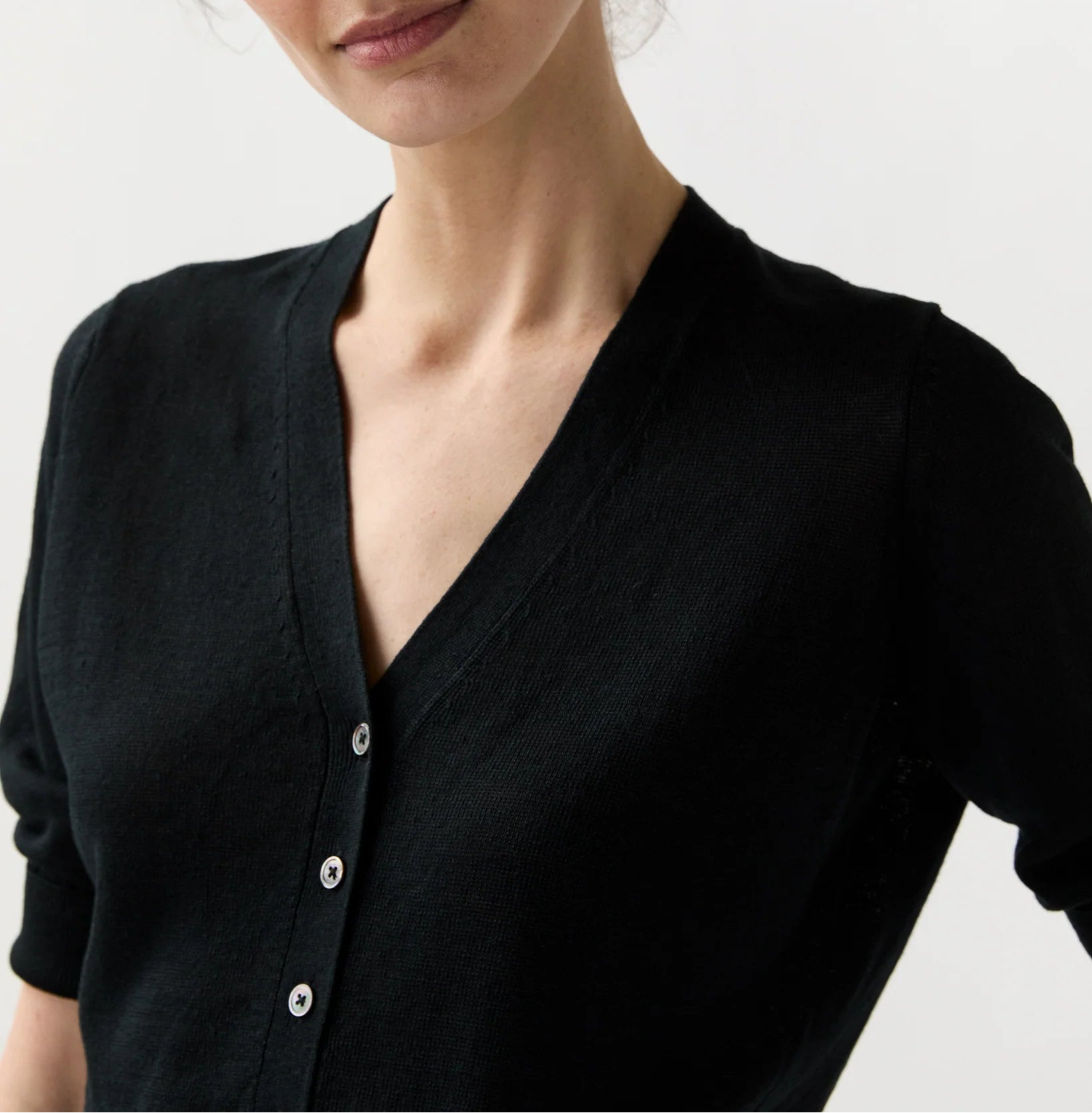 Woman wearing a black cardigan against a plain background