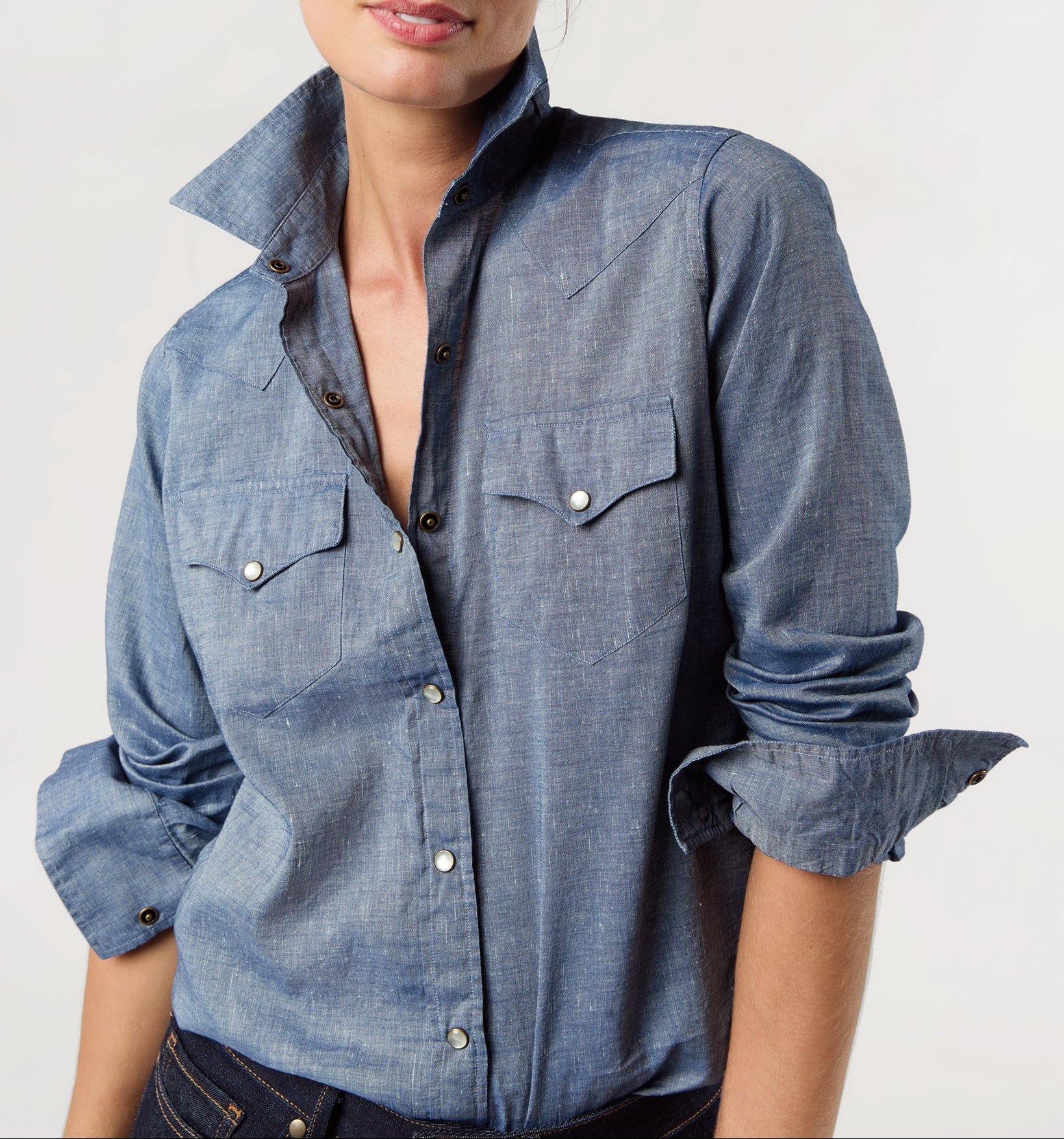 Woman wearing a blue denim shirt on a plain background
