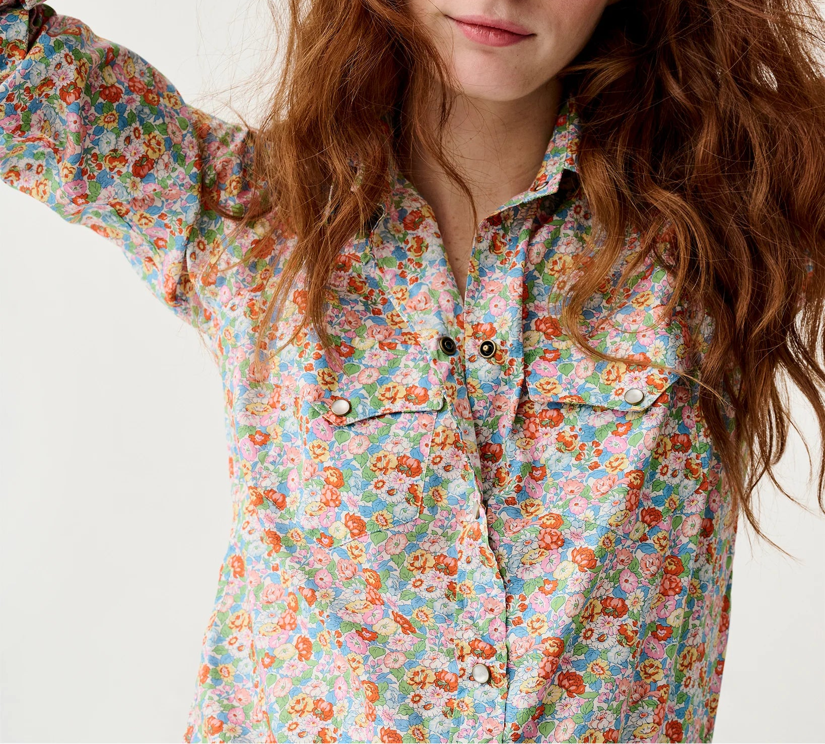 Woman wearing a colorful floral shirt against a plain background