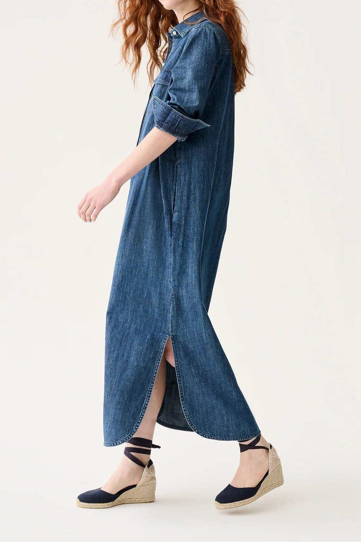 Woman wearing a long denim dress on a white background