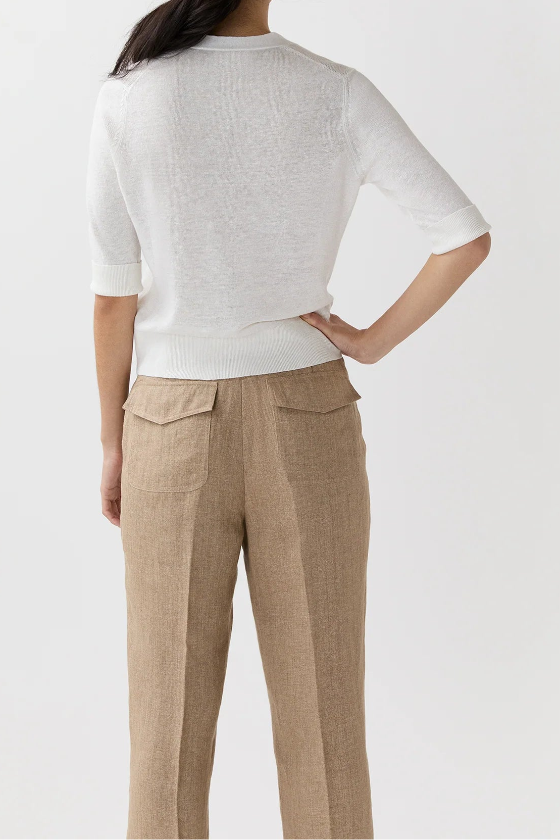 Person wearing a white top and beige pants against a white background