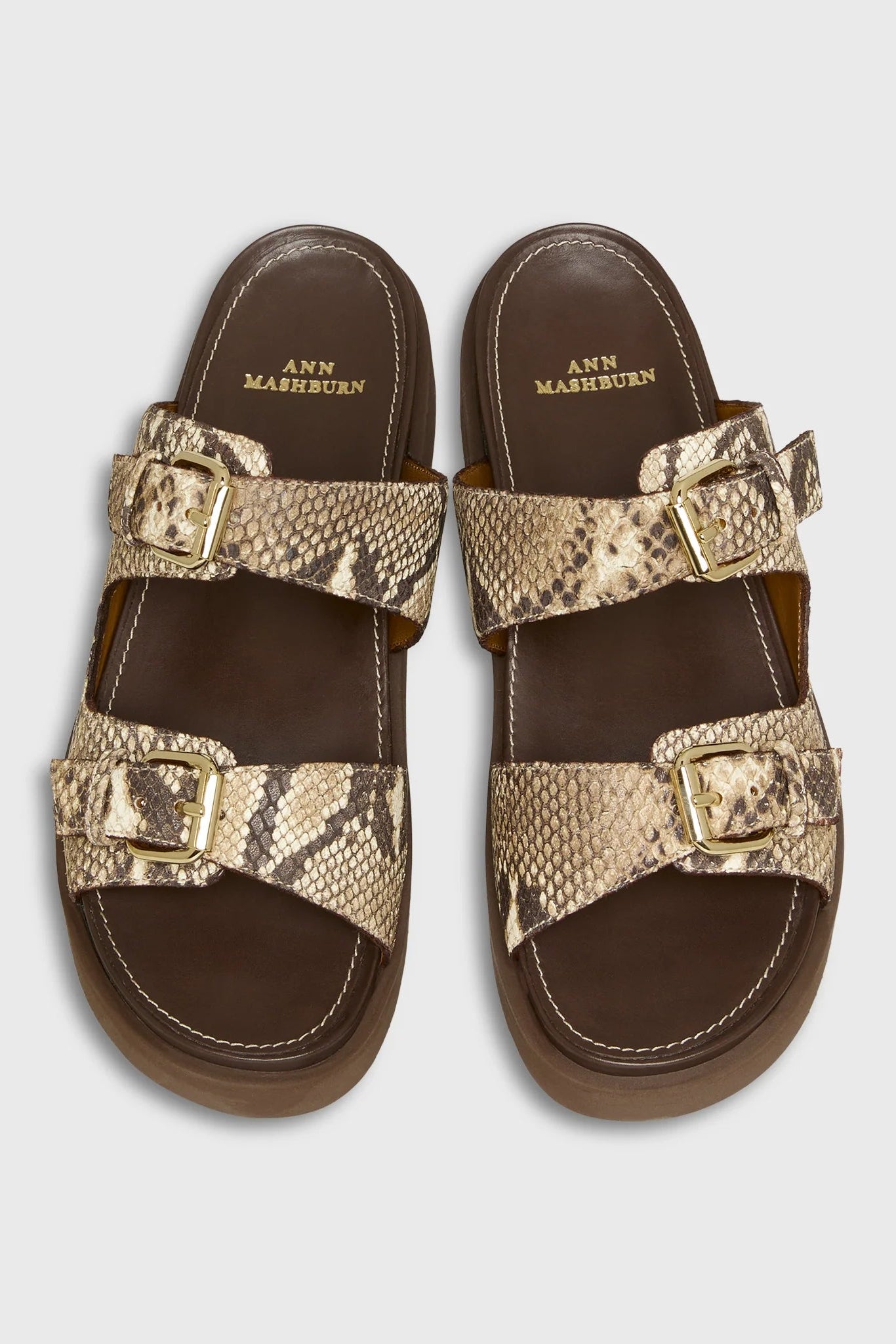 Pair of sandals with snake print straps on a light gray background
