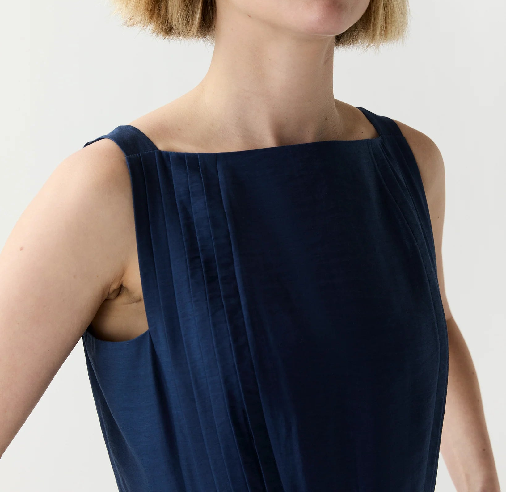 Woman wearing a navy blue sleeveless top against a plain background