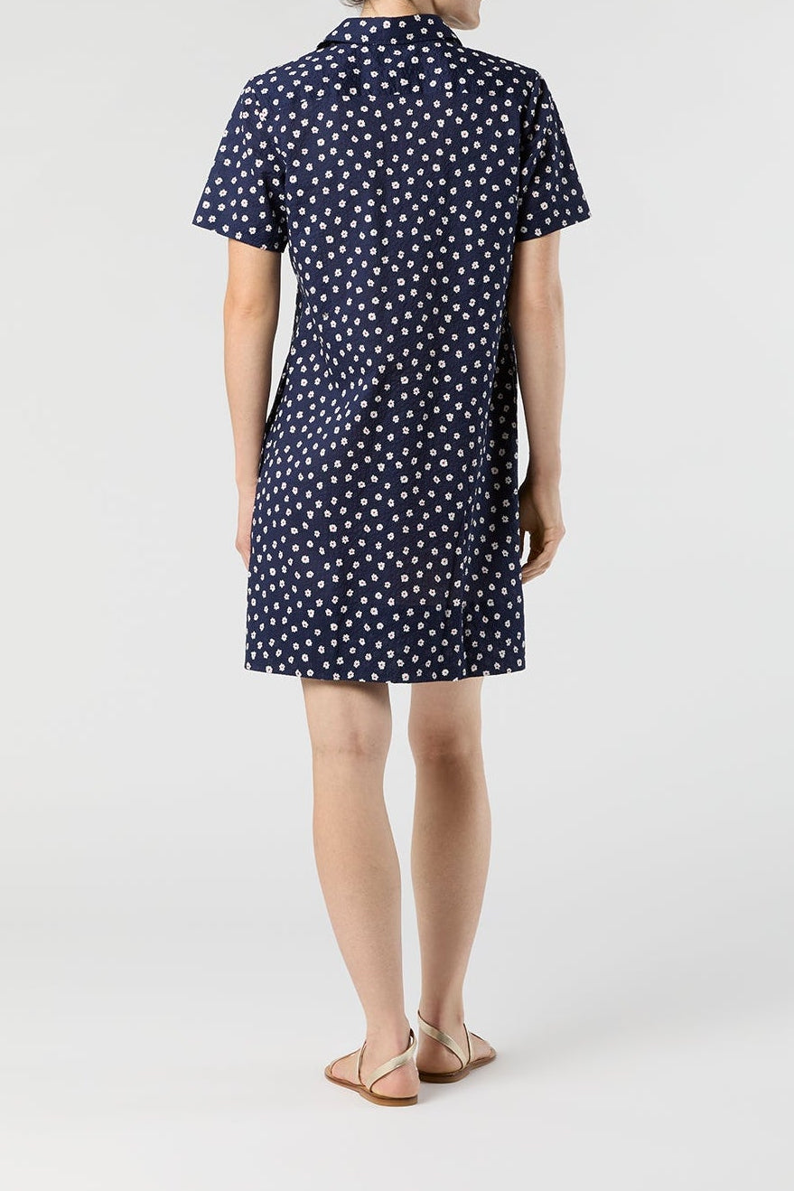 Woman wearing a navy dress with white polka dots on a white background