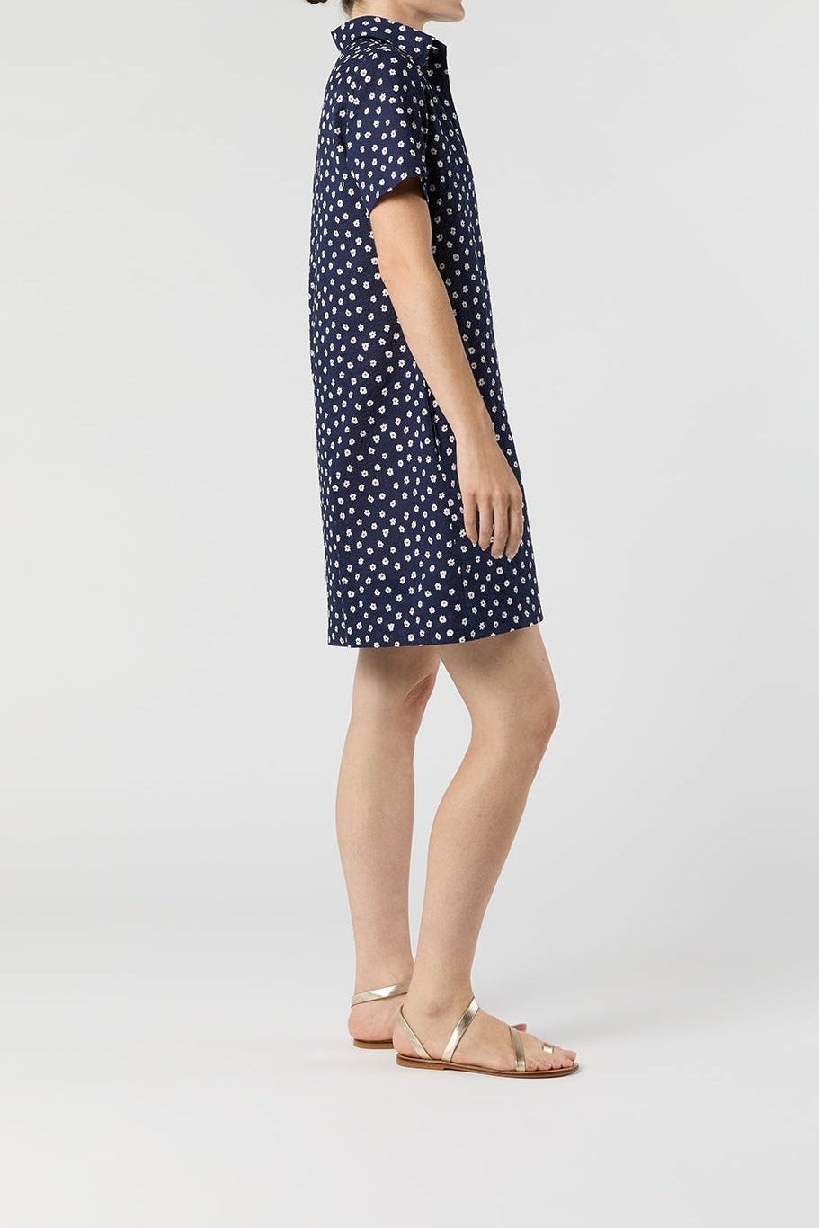 Woman wearing a navy dress with white polka dots on a white background