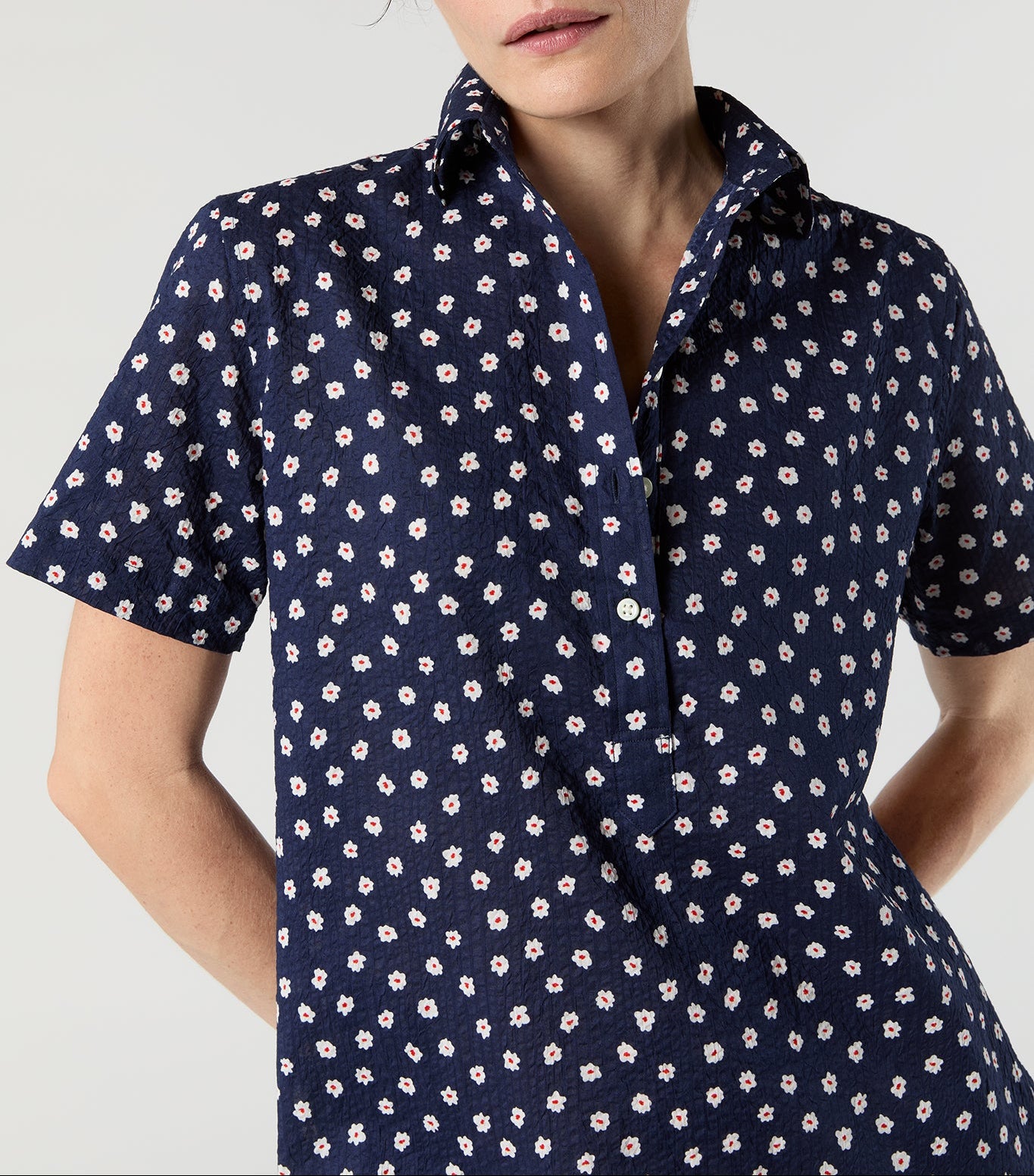 Woman wearing a navy blue shirt with a subtle pattern on a light gray background