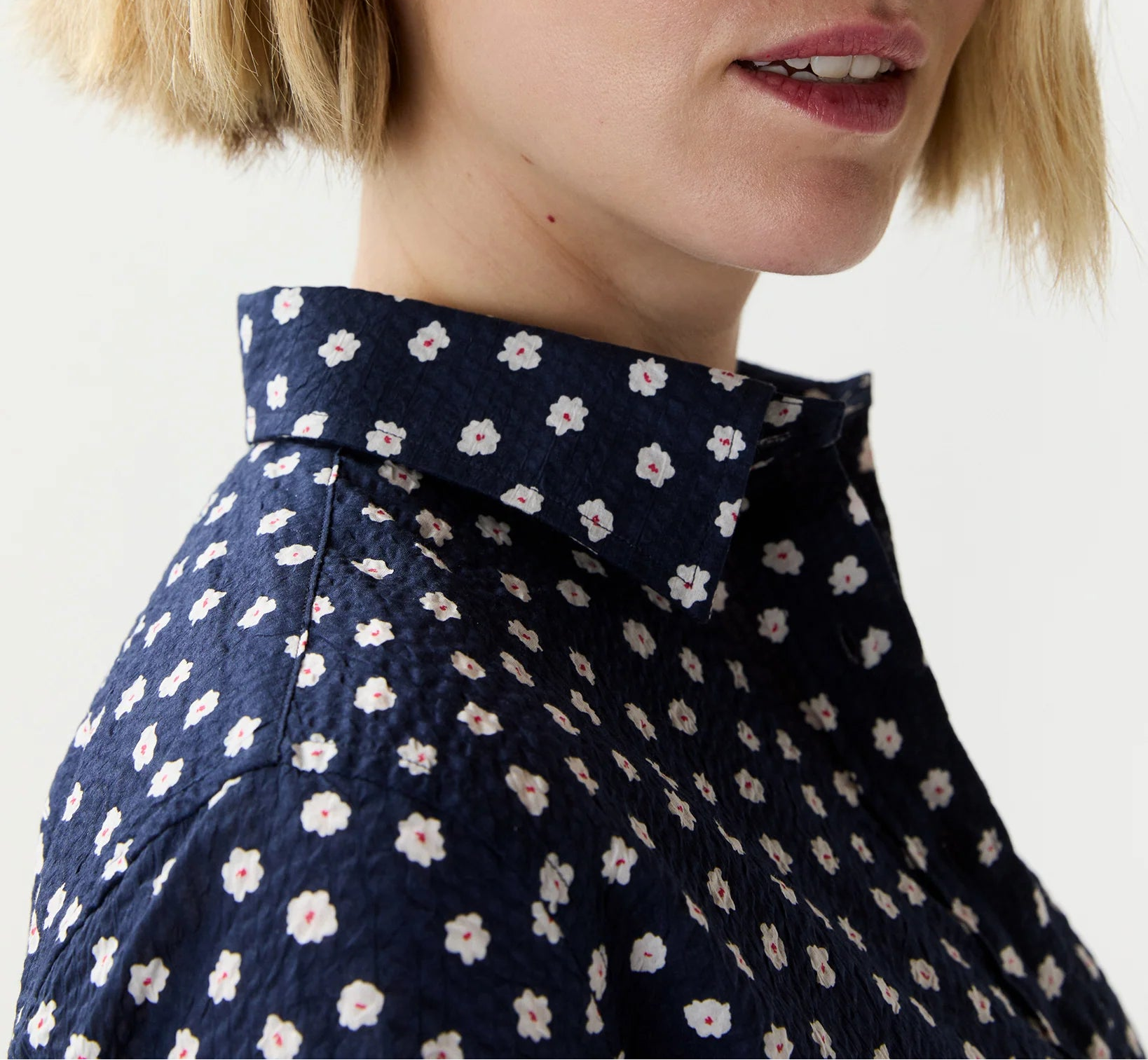 Person wearing a navy blue shirt with white floral pattern on a plain background