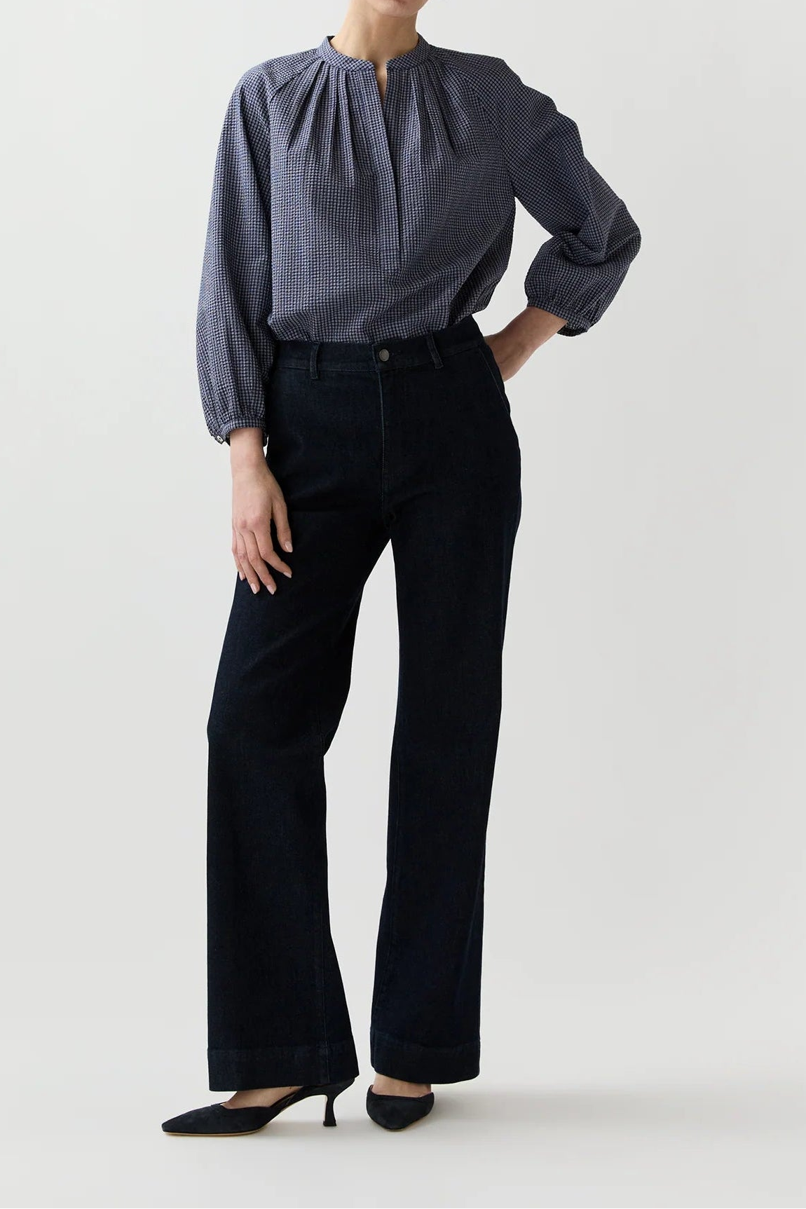 Woman wearing a gray blouse and black pants on a white background